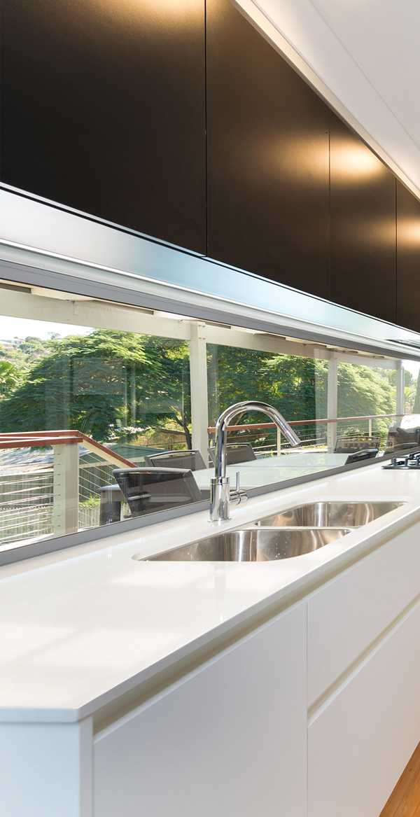 Modern kitchen sink with stainless steel faucets and large window view