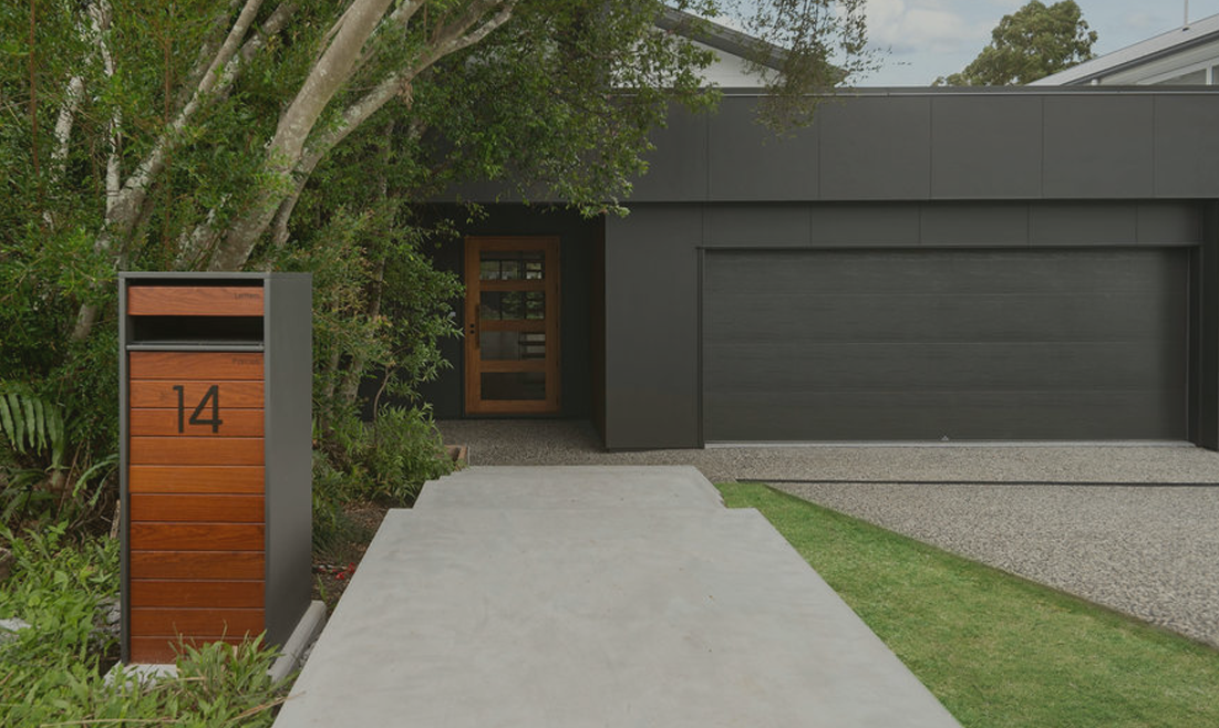 Modern mailbox with number 14 in front of a sleek black house