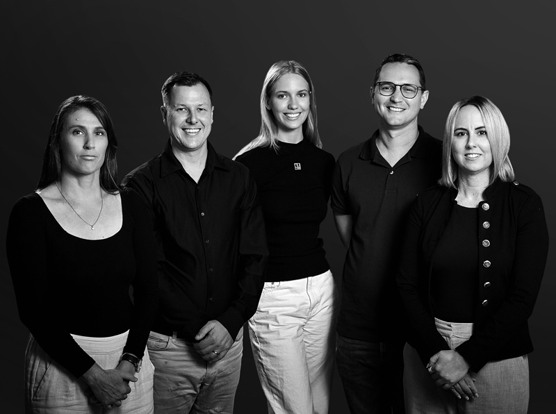 Black and white team portrait of five people standing together