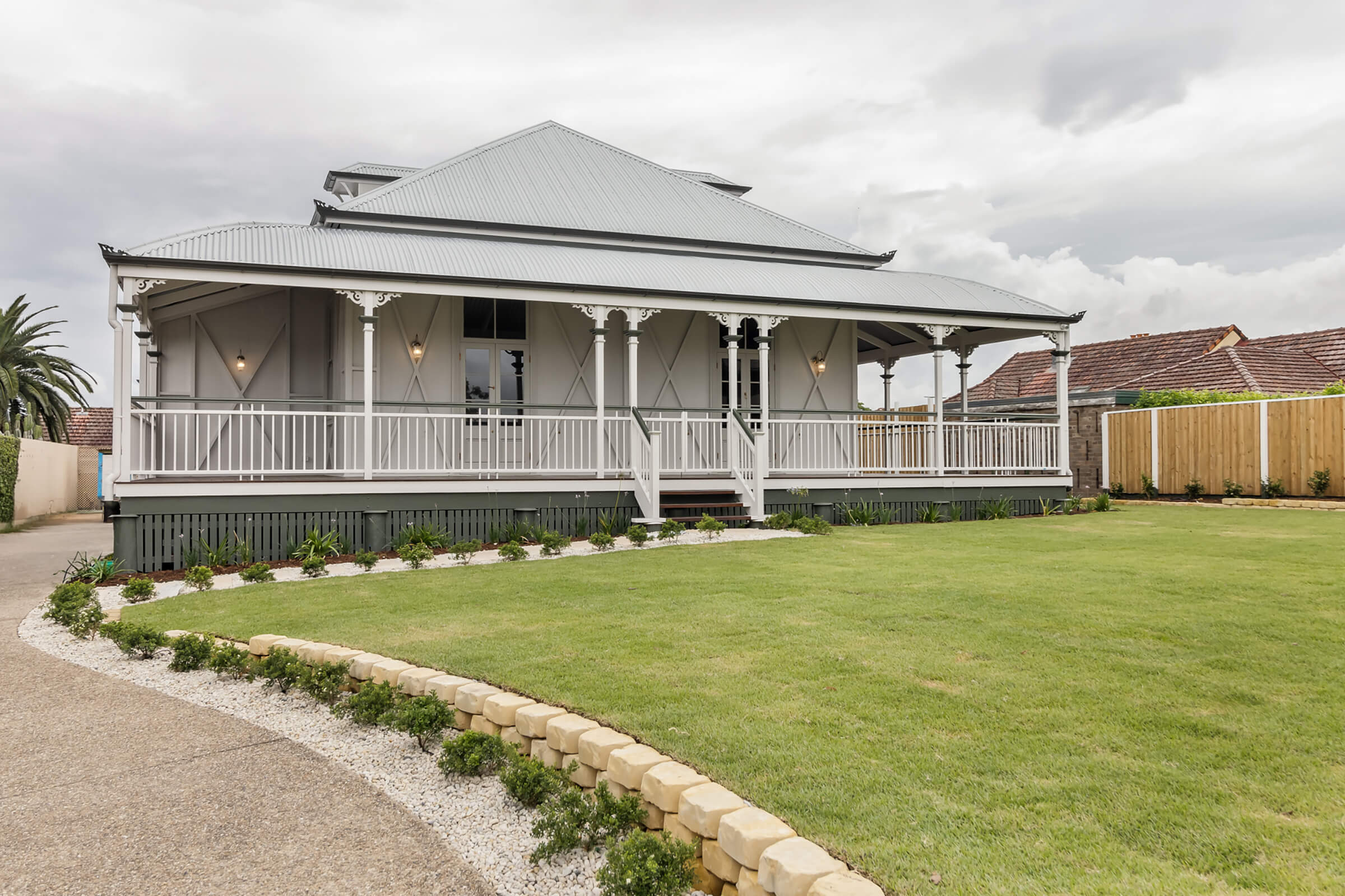 Large traditional home with wraparound veranda, landscaped lawn, and classic exterior detailing.