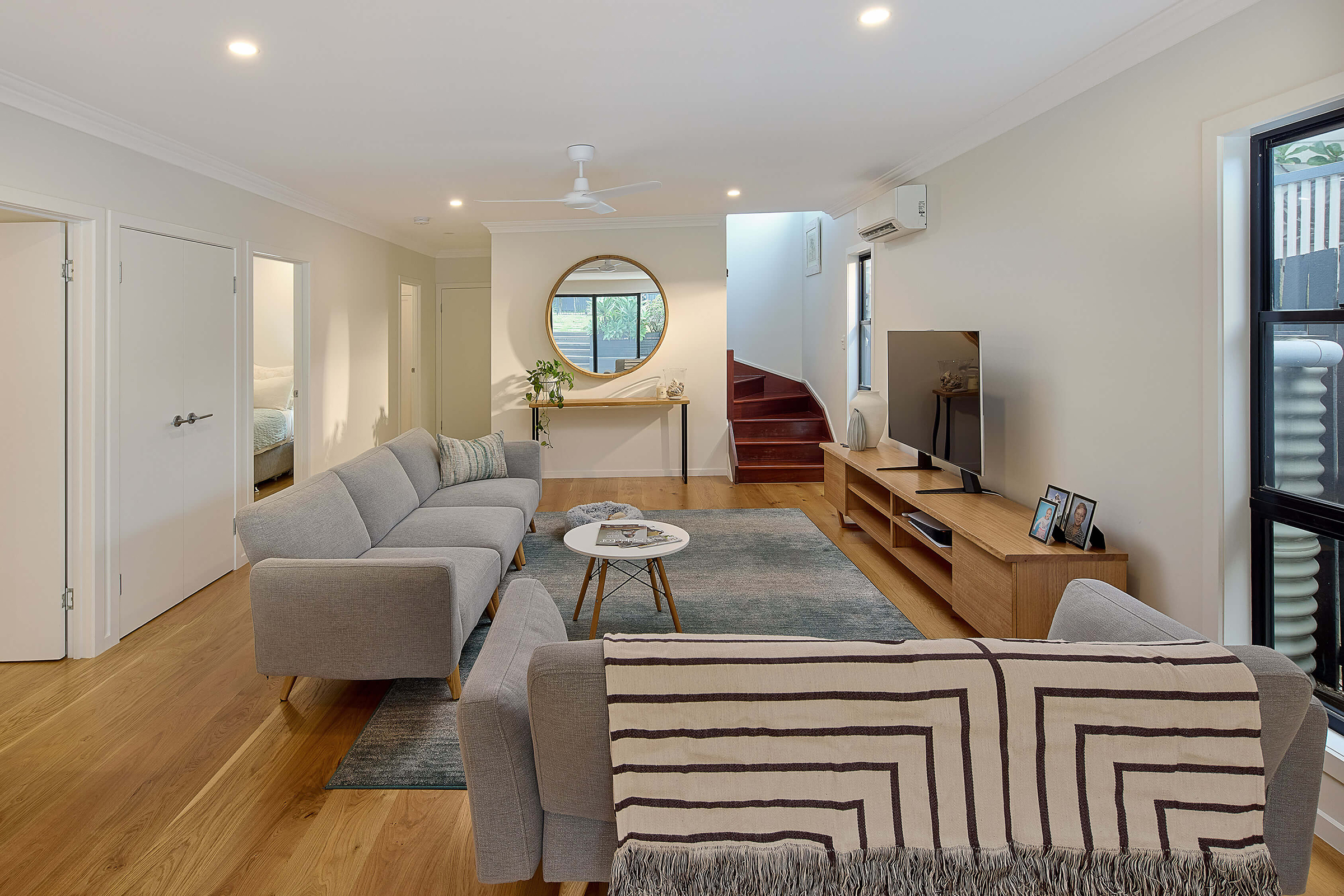 Modern living room with sofa, TV, and staircase