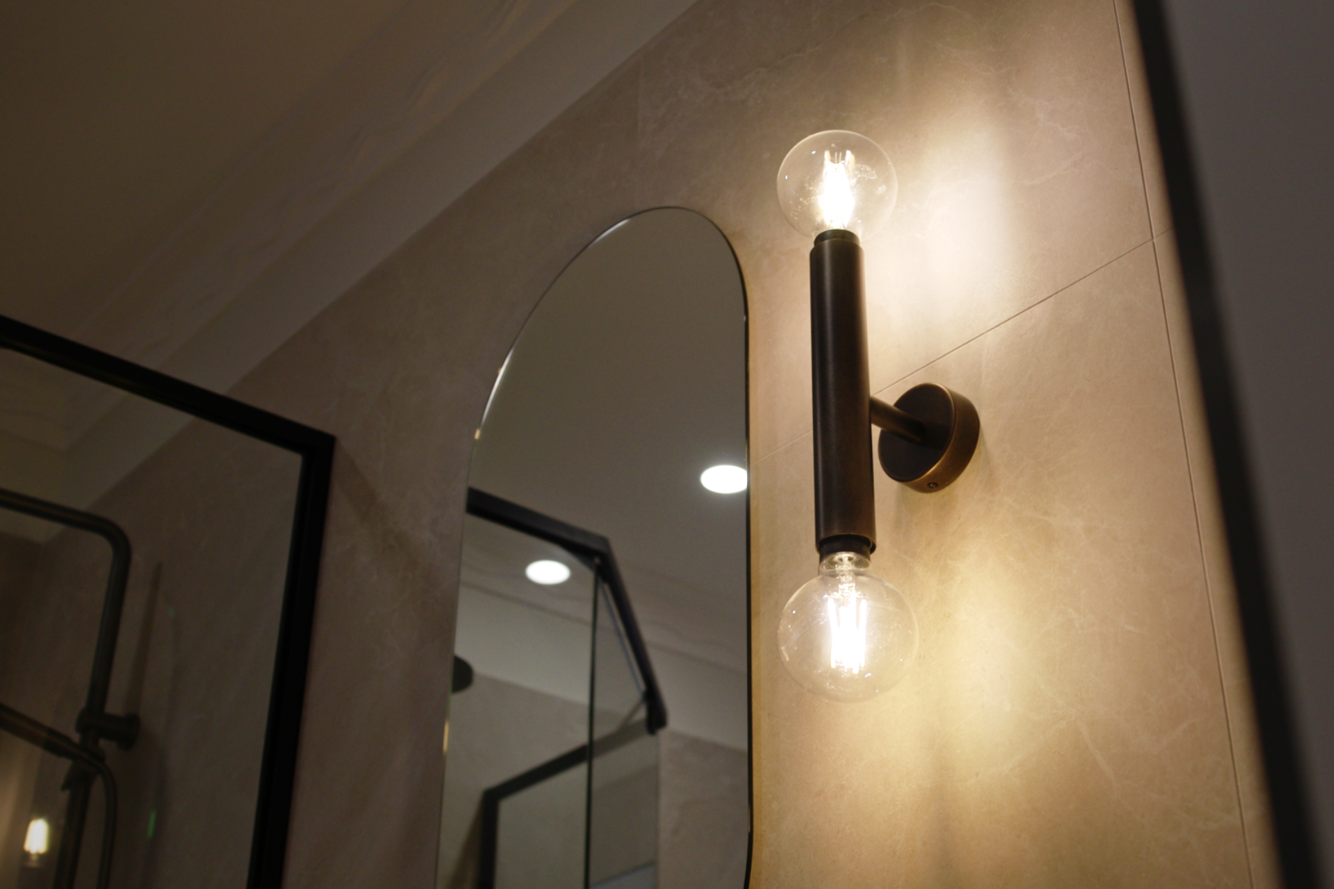 Modern bathroom light fixture and mirror with warm lighting.