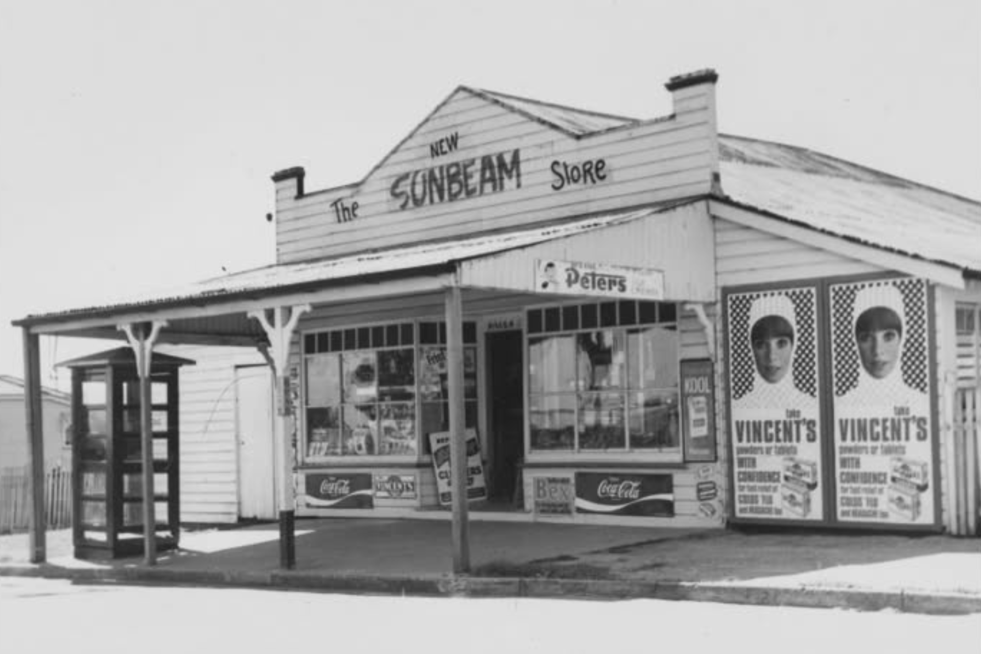 Vintage photo of The Sunbeam Store with advertisements and a phone booth.